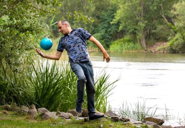 Adam rıhtımda mavi topla oynuyor.