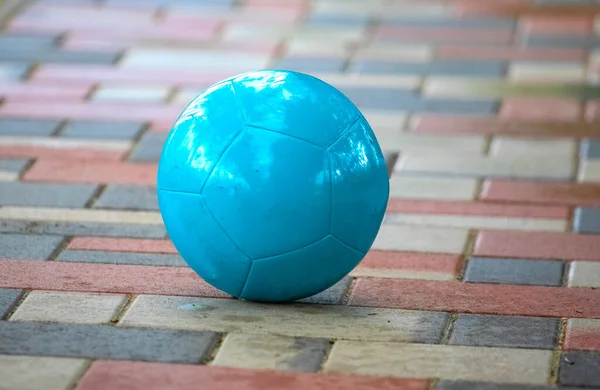 Close-up of blue ball on the colorful paving stones, blurred background