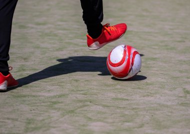 Futbol ya da futbolcunun kırmızı ayakkabılarla topa vuruşu.