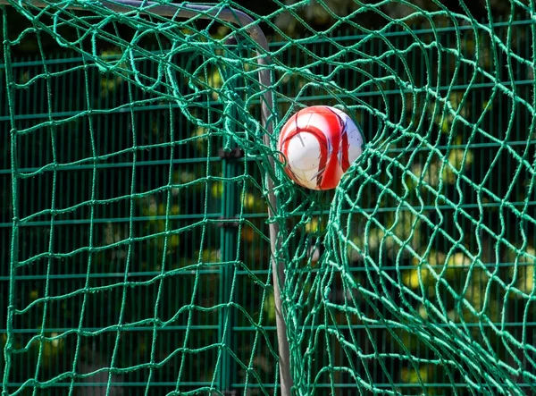 Soccer ball in the green goal net of a soccer goal