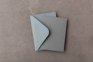 Gri kâğıt şablonu olan boş gri kart beton arka planda maket yapıyor.