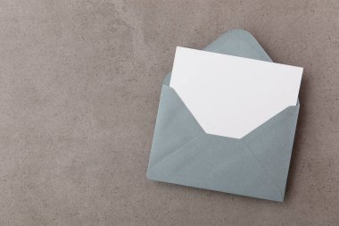 Gri zarflı boş beyaz kart. Beton bir arka plan oluşturur.