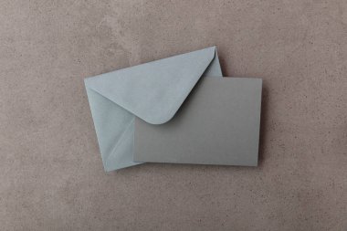 Gri kâğıt şablonu olan boş gri kart beton arka planda maket yapıyor.