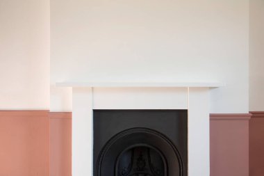 Beyaz ve pembe duvarlarla çevrili Viktorya dönemi ahşap şömine