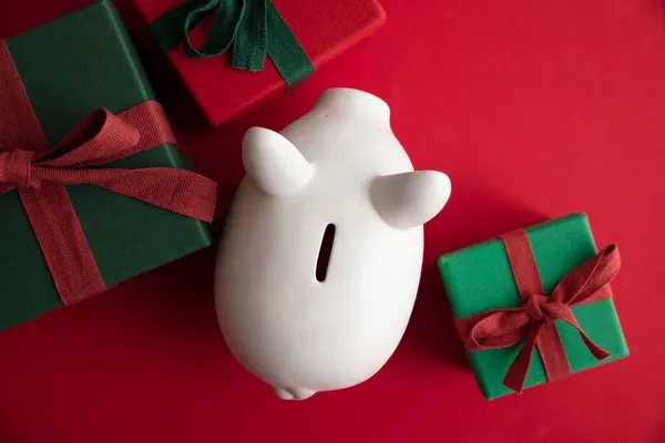 Γιορτή Χριστούγεννα οικονομική αποταμίευση έννοια. Λευκό κουτι χρημάτων κουμπαράς με δώρα — Φωτογραφία Αρχείου