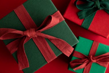 Kırsal bir kurdeleyle bağlanmış ve kırmızı arka planda fiyonklu Noel hediyesi kutusu. Genel Görünüm