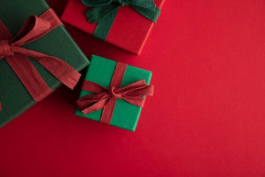 Kırsal bir kurdeleyle bağlanmış ve kırmızı arka planda fiyonklu Noel hediyesi kutusu. Genel Görünüm