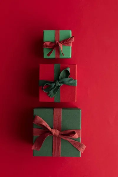 Caixa de presente de Natal festivo presente amarrado com uma fita rústica e arco em um fundo vermelho. Vista aérea — Fotografia de Stock