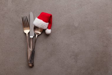 Noel Baba 'nın kırmızı şapkasıyla gümüş çatal ve kaşık. Noel yemeği arkaplanı