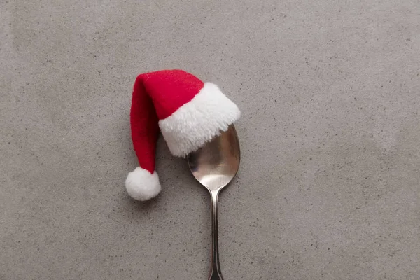 Silver spoon wearing a red Santa hat. Christmas meal background — Stock Photo, Image