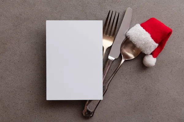 Silver knife fork and spoon with a Santa Claus red festive hat. Christmas meal background — Stock Photo, Image