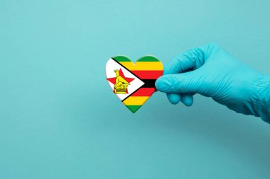 Medical workers hand wearing surgical glove holding Zimbabwe flag heart clipart