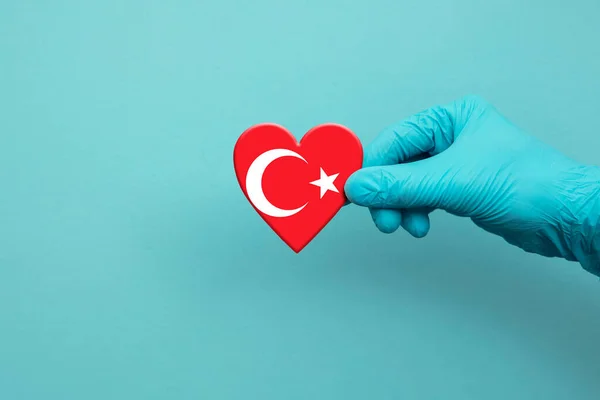 Trabalhadores médicos mão vestindo luva cirúrgica segurando coração bandeira Turquia — Fotografia de Stock