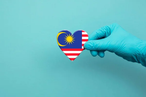 의사들 이 말레이시아 국기를 들고 수술용 장갑을 끼고 있다 — 스톡 사진