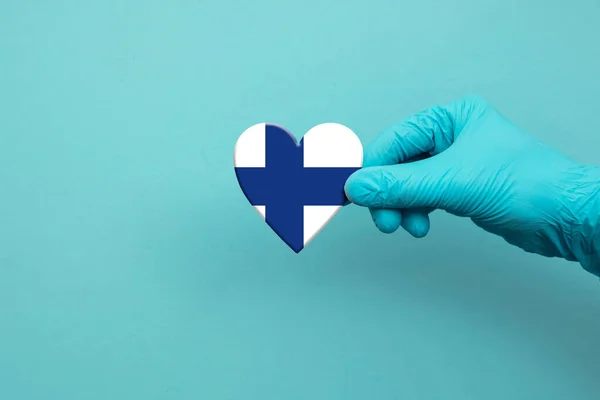 Orvosi dolgozók kéz visel sebészeti kesztyű gazdaság Finnország zászló szív — Stock Fotó