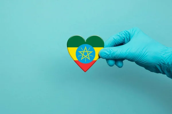 Medical workers hand wearing surgical glove holding Ethiopia flag heart — Foto Stock