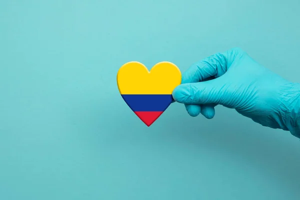 Medical workers hand wearing surgical glove holding Colombia flag heart — Stockfoto