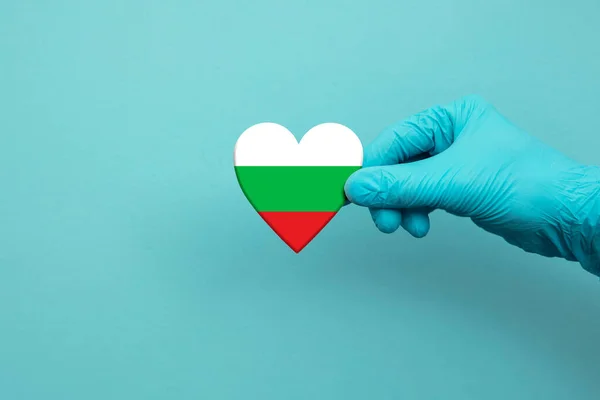 Pekerja medis tangan mengenakan sarung tangan bedah memegang bendera Bulgaria jantung — Stok Foto