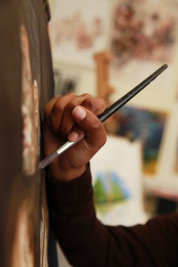 Bir çocuğun elinde boya fırçasıyla resim çizerken..