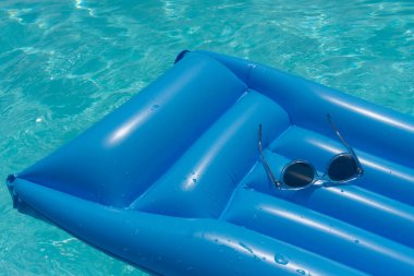 Mavi yüzme havuzunda güneş gözlüğü. Yaz tatili geçmişi.