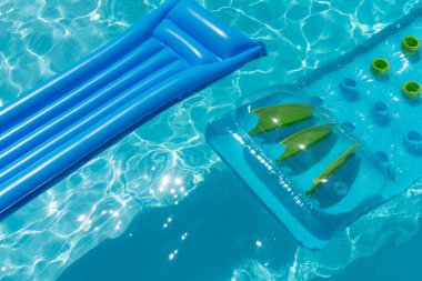 Clear blue summer pool lounger float on a rippled swimming pool.