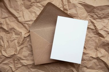 Blank card with kraft brown paper envelope template mock up on crumpled brown paper.