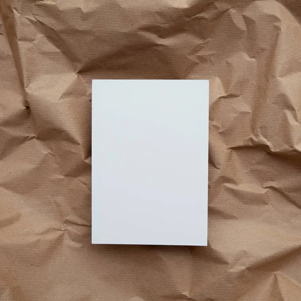 Blank white invitation letter template mock up on crumpled brown paper.