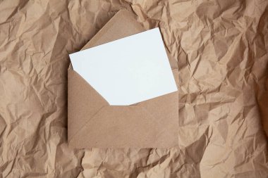 Blank card with kraft brown paper envelope template mock up on crumpled brown paper.