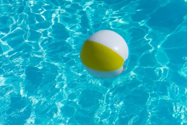 Inflatable beach ball floating on a summer swimming pool.