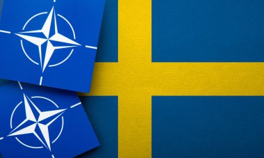 LONDON, UK - August 2022: NATO North Atlantic Treaty Organization military alliance logo on a Sweden flag.