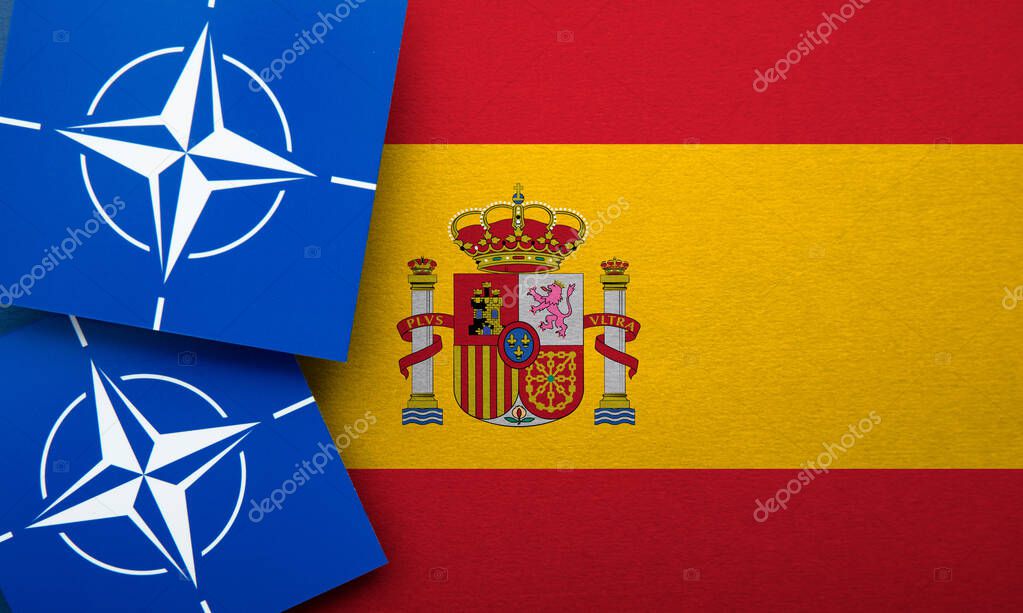 LONDON, UK - August 2022: NATO North Atlantic Treaty Organization military alliance logo on a Spain flag.