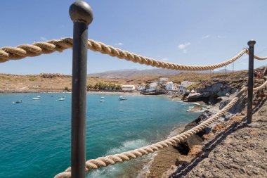 Geleneksel balıkçı koyunun manzarası, balıkçıların evleri, geleneksel balıkçı tekneleri ve kum ve arka planda dağlar olan çakıl taşı plajı..