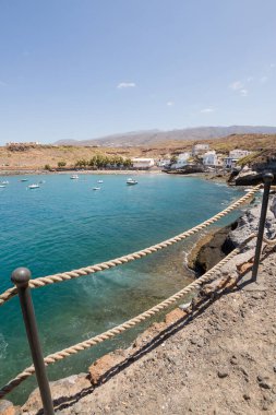 Geleneksel balıkçı koyunun manzarası, balıkçıların evleri, geleneksel balıkçı tekneleri ve kum ve arka planda dağlar olan çakıl taşı plajı..
