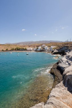 Geleneksel balıkçı koyunun manzarası, balıkçıların evleri, geleneksel balıkçı tekneleri ve kum ve arka planda dağlar olan çakıl taşı plajı..