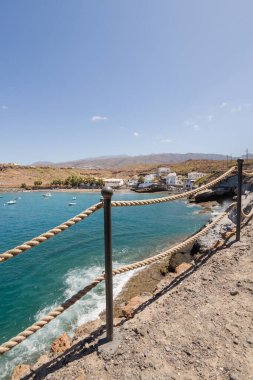 Geleneksel balıkçı koyunun manzarası, balıkçıların evleri, geleneksel balıkçı tekneleri ve kum ve arka planda dağlar olan çakıl taşı plajı..