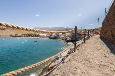 Geleneksel balıkçı koyunun manzarası, balıkçıların evleri, geleneksel balıkçı tekneleri ve kum ve arka planda dağlar olan çakıl taşı plajı..