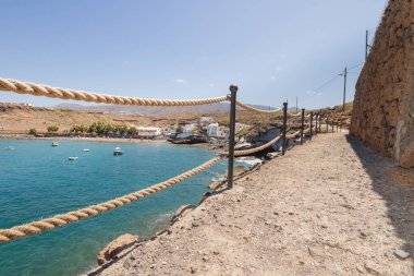 Geleneksel balıkçı koyunun manzarası, balıkçıların evleri, geleneksel balıkçı tekneleri ve kum ve arka planda dağlar olan çakıl taşı plajı..