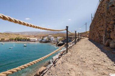 Geleneksel balıkçı koyunun manzarası, balıkçıların evleri, geleneksel balıkçı tekneleri ve kum ve arka planda dağlar olan çakıl taşı plajı..