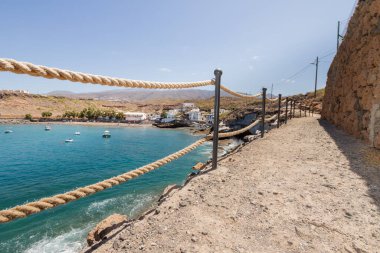 Geleneksel balıkçı koyunun manzarası, balıkçıların evleri, geleneksel balıkçı tekneleri ve kum ve arka planda dağlar olan çakıl taşı plajı..
