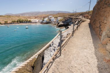 Geleneksel balıkçı koyunun manzarası, balıkçıların evleri, geleneksel balıkçı tekneleri ve kum ve arka planda dağlar olan çakıl taşı plajı..