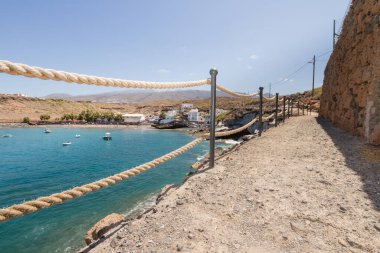 Geleneksel balıkçı koyunun manzarası, balıkçıların evleri, geleneksel balıkçı tekneleri ve kum ve arka planda dağlar olan çakıl taşı plajı..