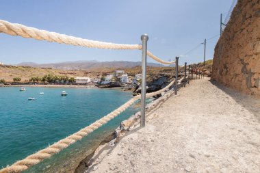 Geleneksel balıkçı koyunun manzarası, balıkçıların evleri, geleneksel balıkçı tekneleri ve kum ve arka planda dağlar olan çakıl taşı plajı..