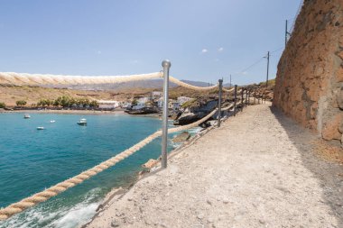 Geleneksel balıkçı koyunun manzarası, balıkçıların evleri, geleneksel balıkçı tekneleri ve kum ve arka planda dağlar olan çakıl taşı plajı..