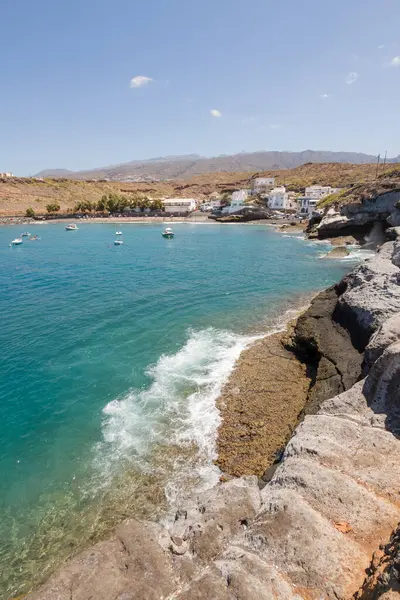 Geleneksel balıkçı koyunun manzarası, balıkçıların evleri, geleneksel balıkçı tekneleri ve kum ve arka planda dağlar olan çakıl taşı plajı..