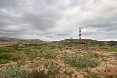 Volkanik kayalar, deniz feneri ve fırtına bulutlarıyla çöl manzarası. Aabdes, Tenerife, Kanarya Adaları. İspanya