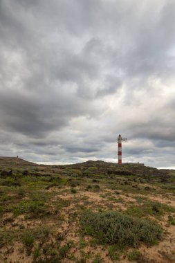 Volkanik kayalar, deniz feneri ve fırtına bulutlarıyla çöl manzarası. Aabdes, Tenerife, Kanarya Adaları. İspanya