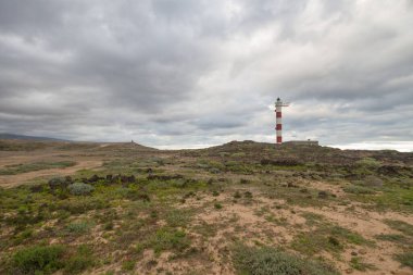 Volkanik kayalar, deniz feneri ve fırtına bulutlarıyla çöl manzarası. Aabdes, Tenerife, Kanarya Adaları. İspanya