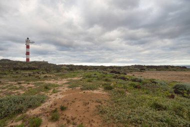 Volkanik kayalar, deniz feneri ve fırtına bulutlarıyla çöl manzarası. Aabdes, Tenerife, Kanarya Adaları. İspanya