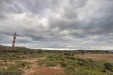 Volkanik kayalar, deniz feneri ve fırtına bulutlarıyla çöl manzarası. Aabdes, Tenerife, Kanarya Adaları. İspanya