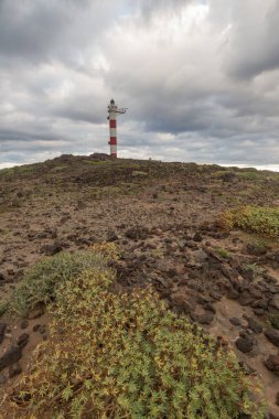 Volkanik kayalar, deniz feneri ve fırtına bulutlarıyla çöl manzarası. Aabdes, Tenerife, Kanarya Adaları. İspanya